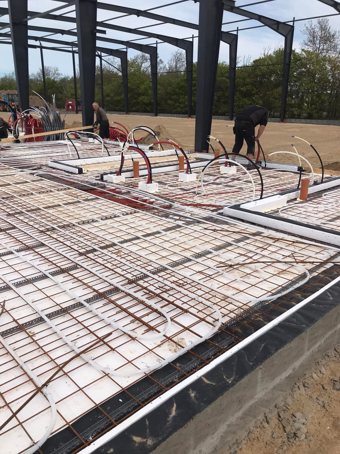 Arbejder installerer gulvvarme i bygningsfundament