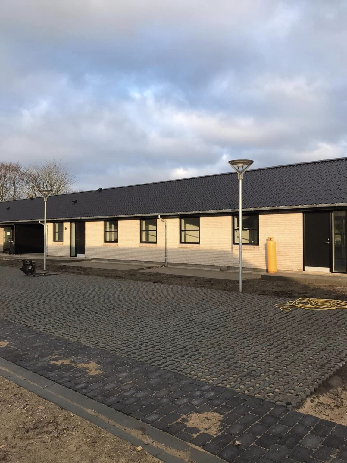 Nybygget rækkehus med mørkt tag og flisebelægning