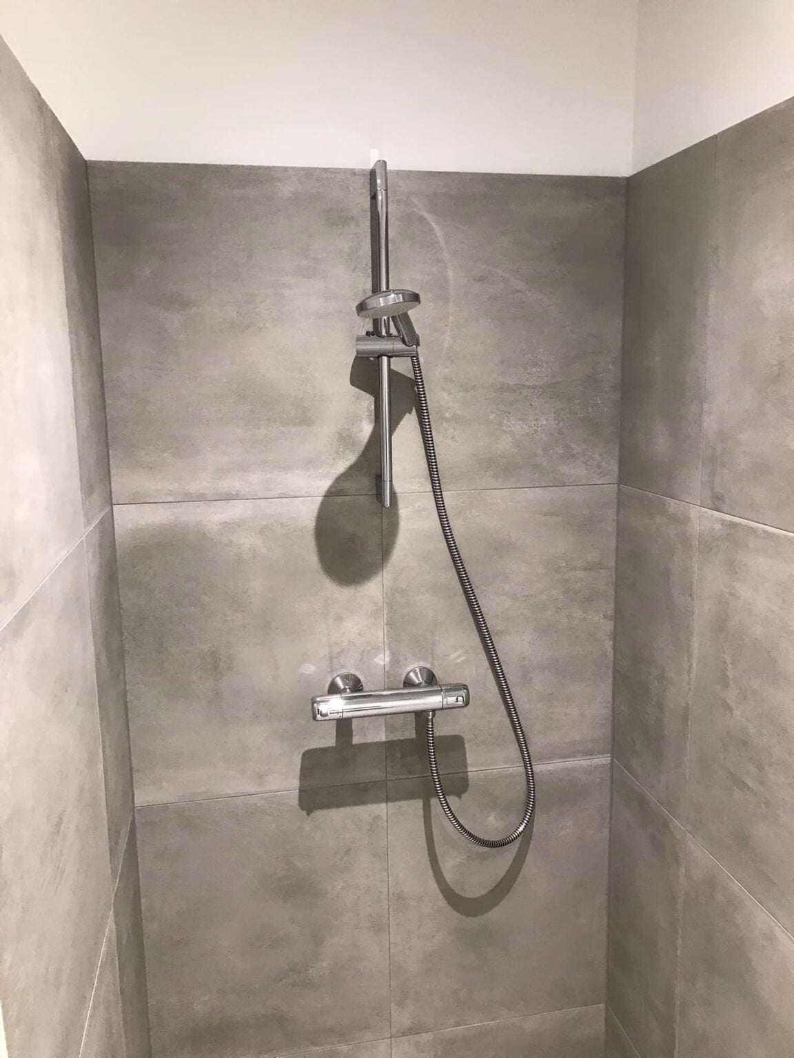 Moderne brusekabine med grå fliser og bruser