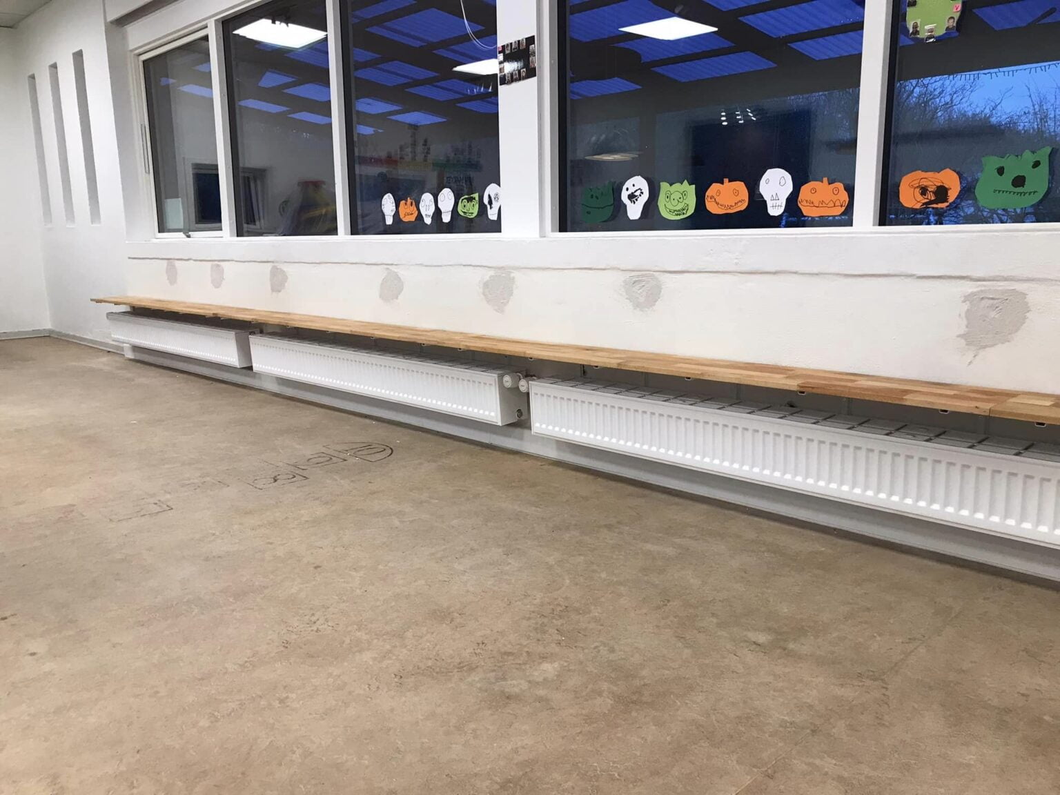 Bænk foran vinduer med farverige papirfigurer