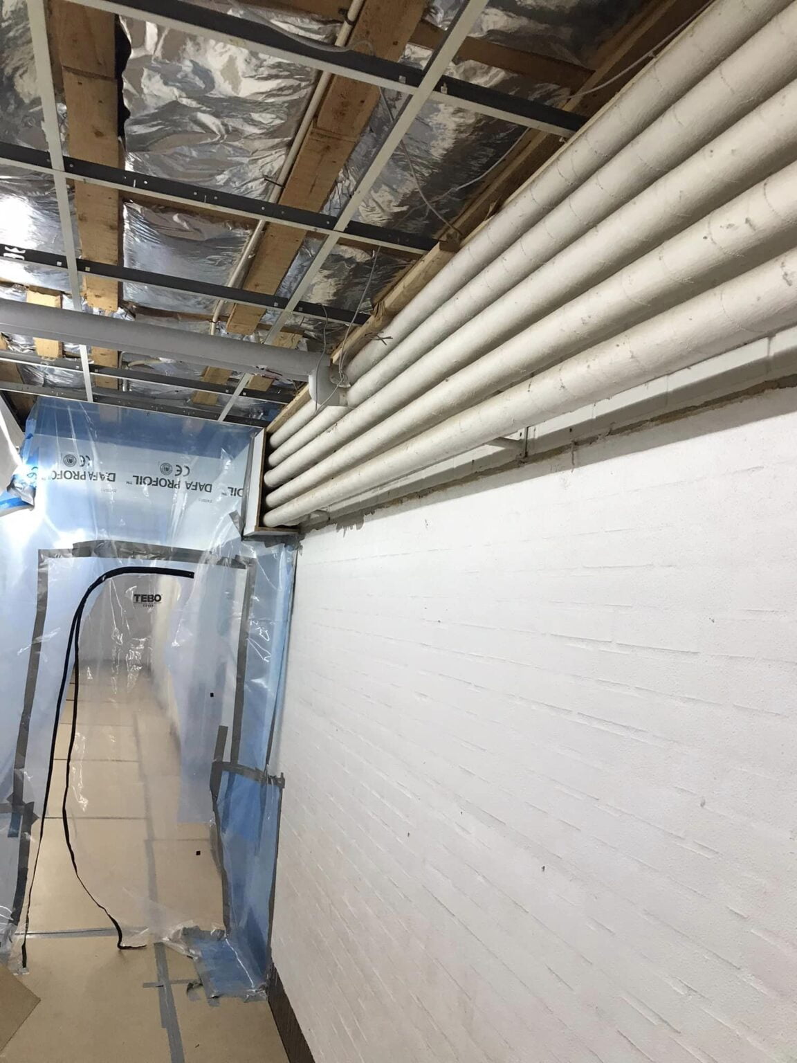 Renovering af kældergang med rør og plastafdækning