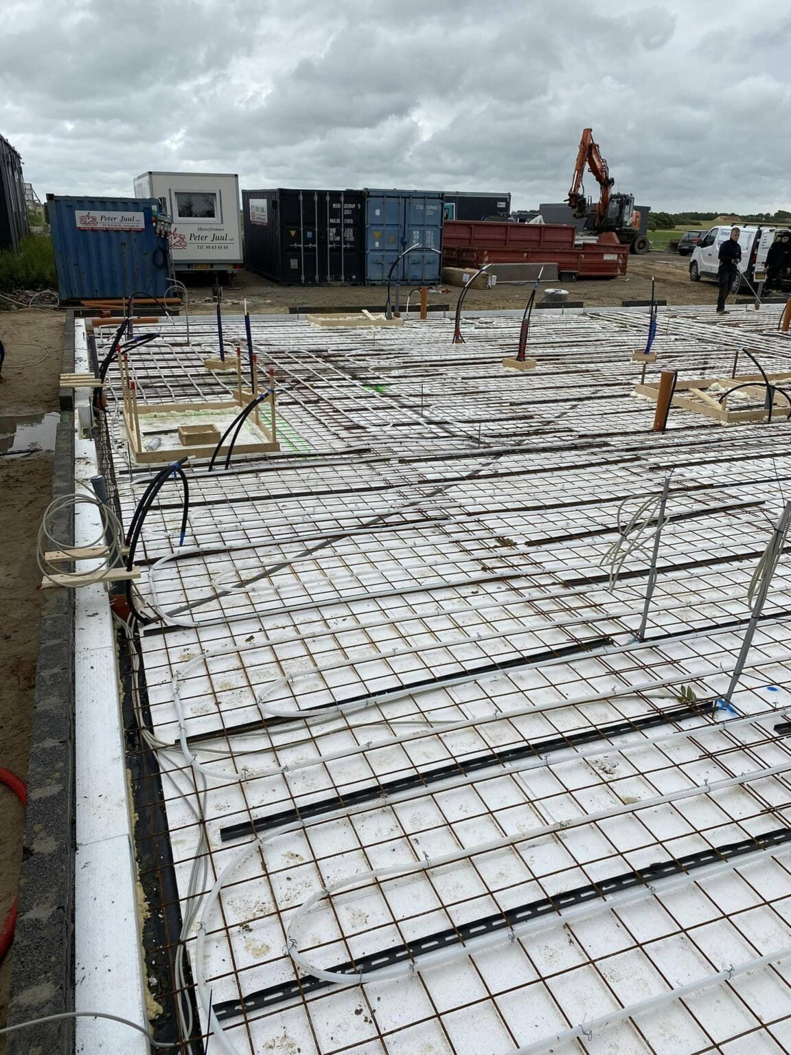 Betonfundament under opførelse med armeringsnet og rørføring