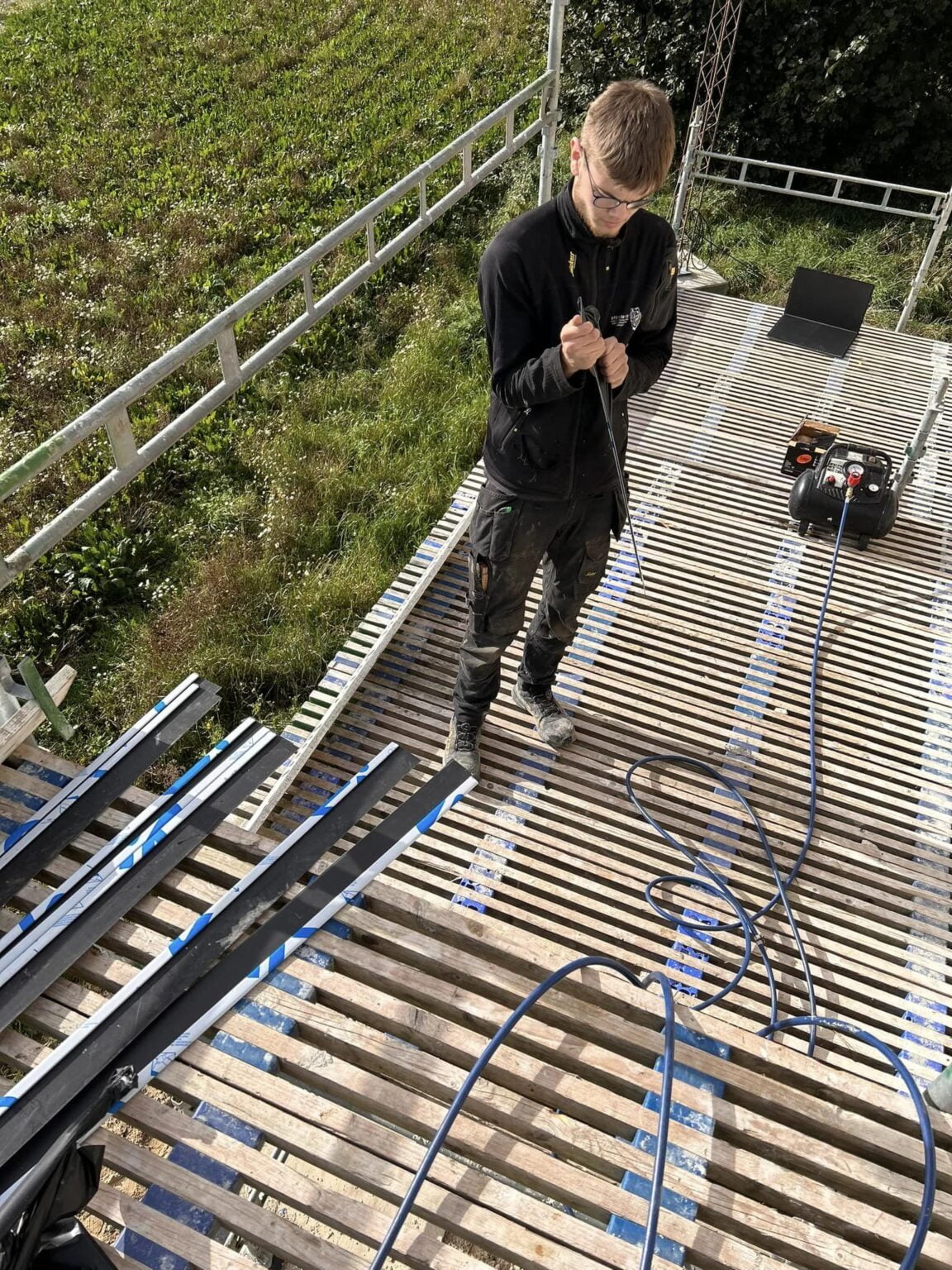 Håndværker arbejder på stillads med kabler og værktøj