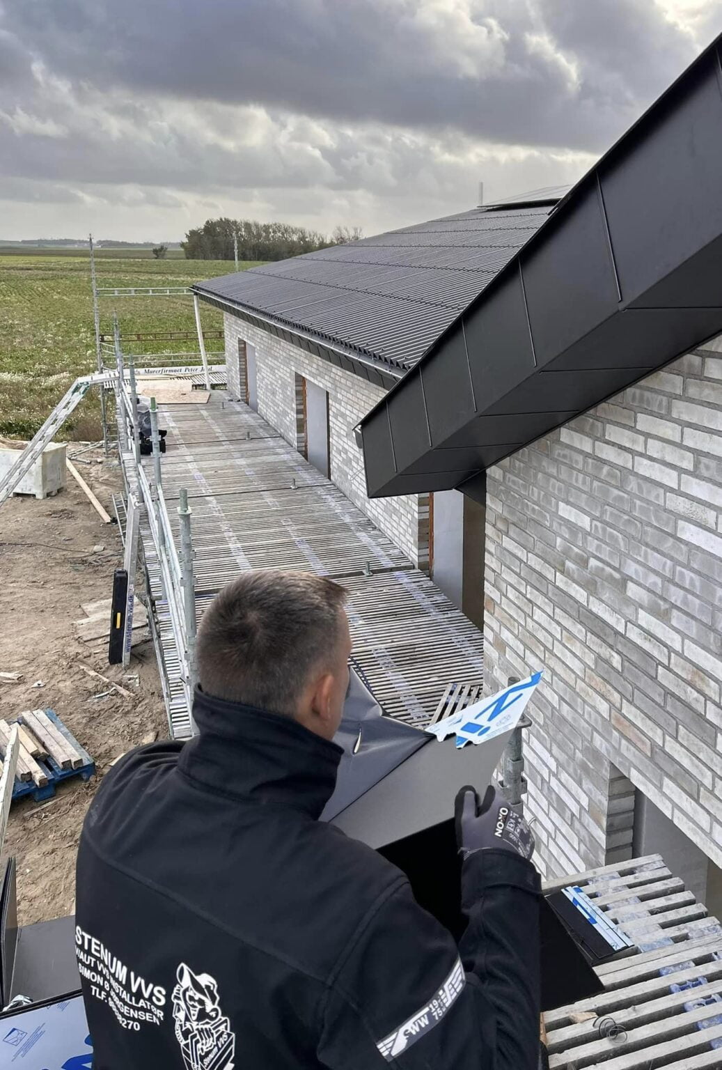 Håndværker installerer tagrender på moderne bygning