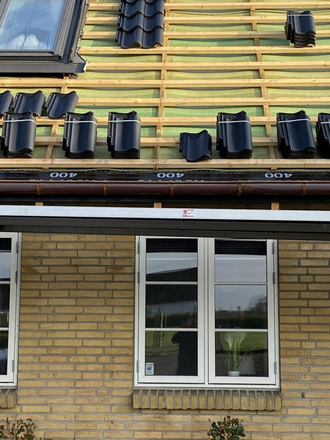 Taglægning på gul murstenshus med sorte tegl