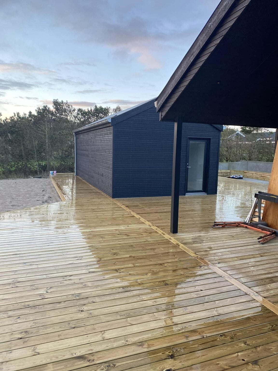 Nybygget træterrasse ved mørkeblåt hus