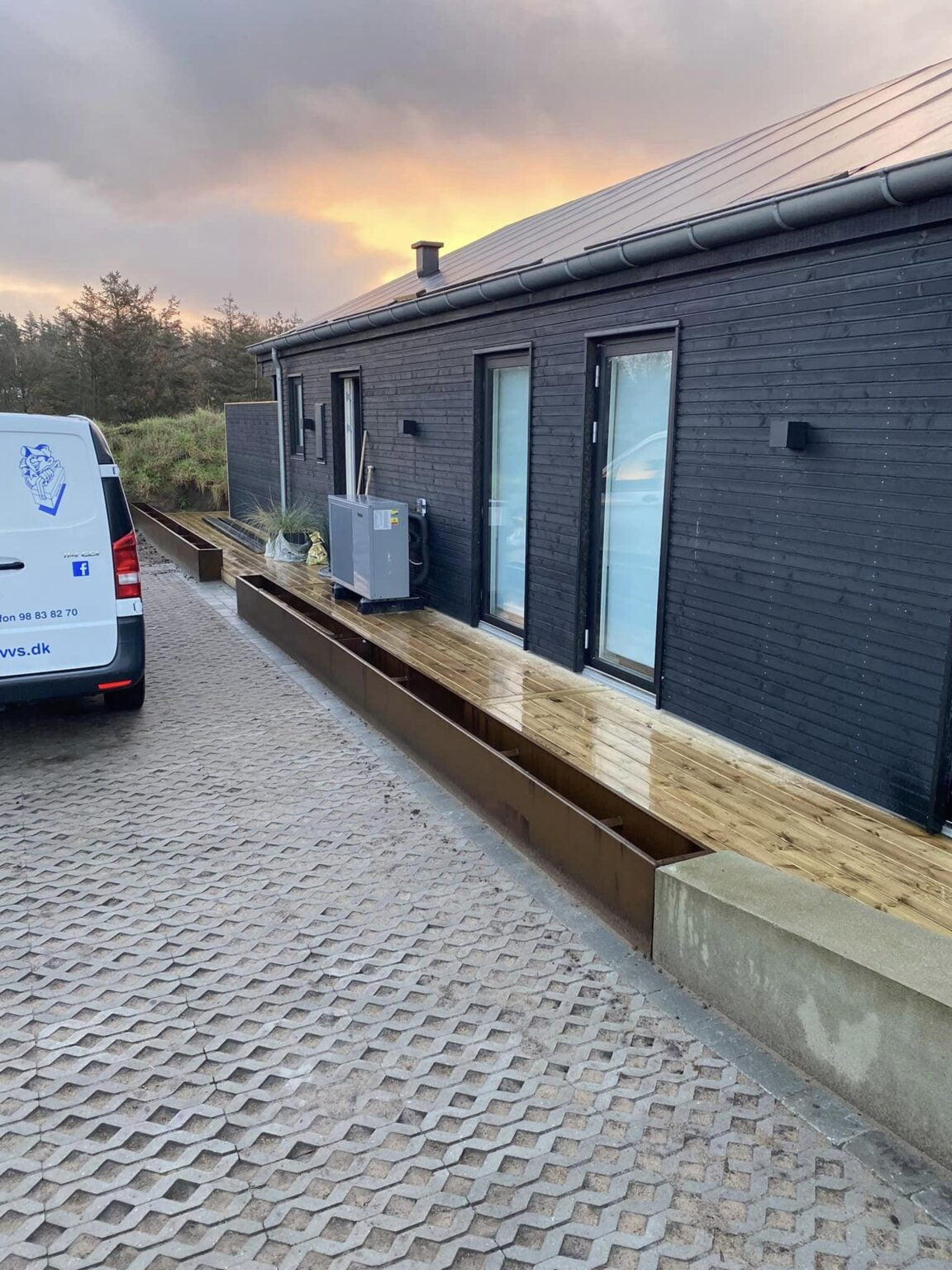 Moderne sort træhus med terrasse ved solnedgang