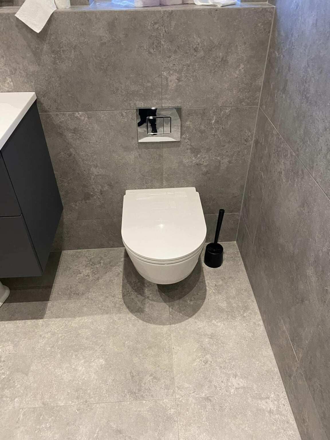 Moderne badeværelse med væghængt toilet og grå fliser