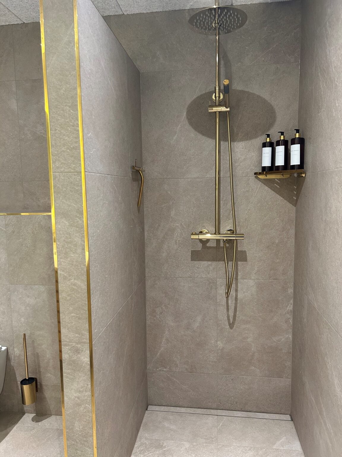 Moderne brusekabine med guldarmatur og flisevægge