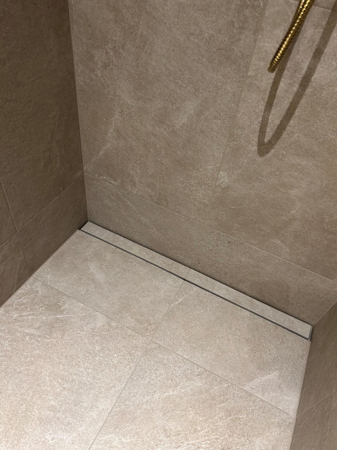 Moderne bruseområde med beige fliser og linjeafløb