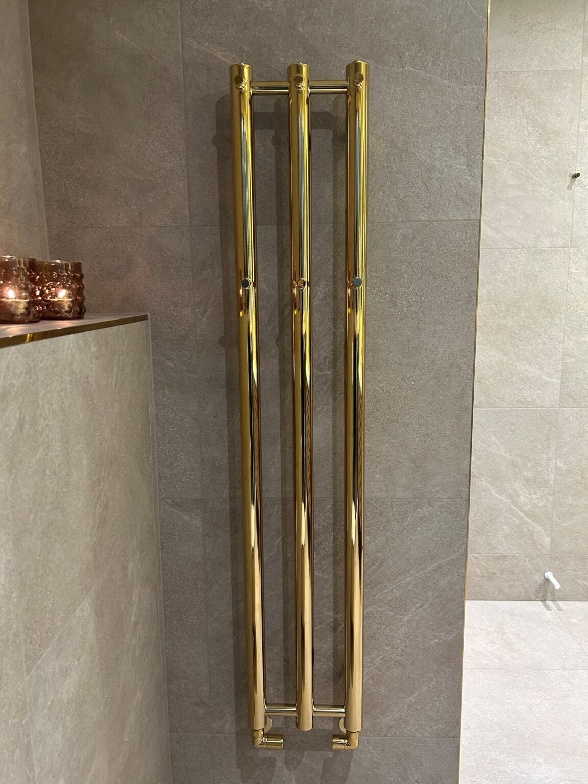 Gylden håndklædevarmer på badeværelsesvæg med fliser